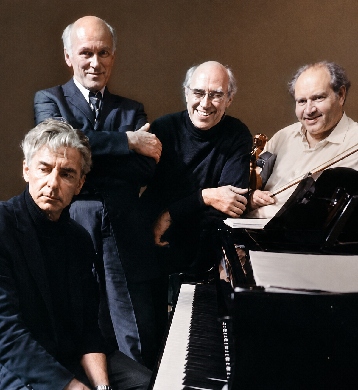 Musicians gathered around a piano in conversation and rehearsal